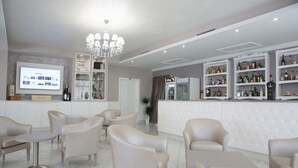 A modern lounge area with leather sofas, a bar with shelves of liquor, and a television screen displaying content. - Hotel Leon (San Giovanni Rotondo)