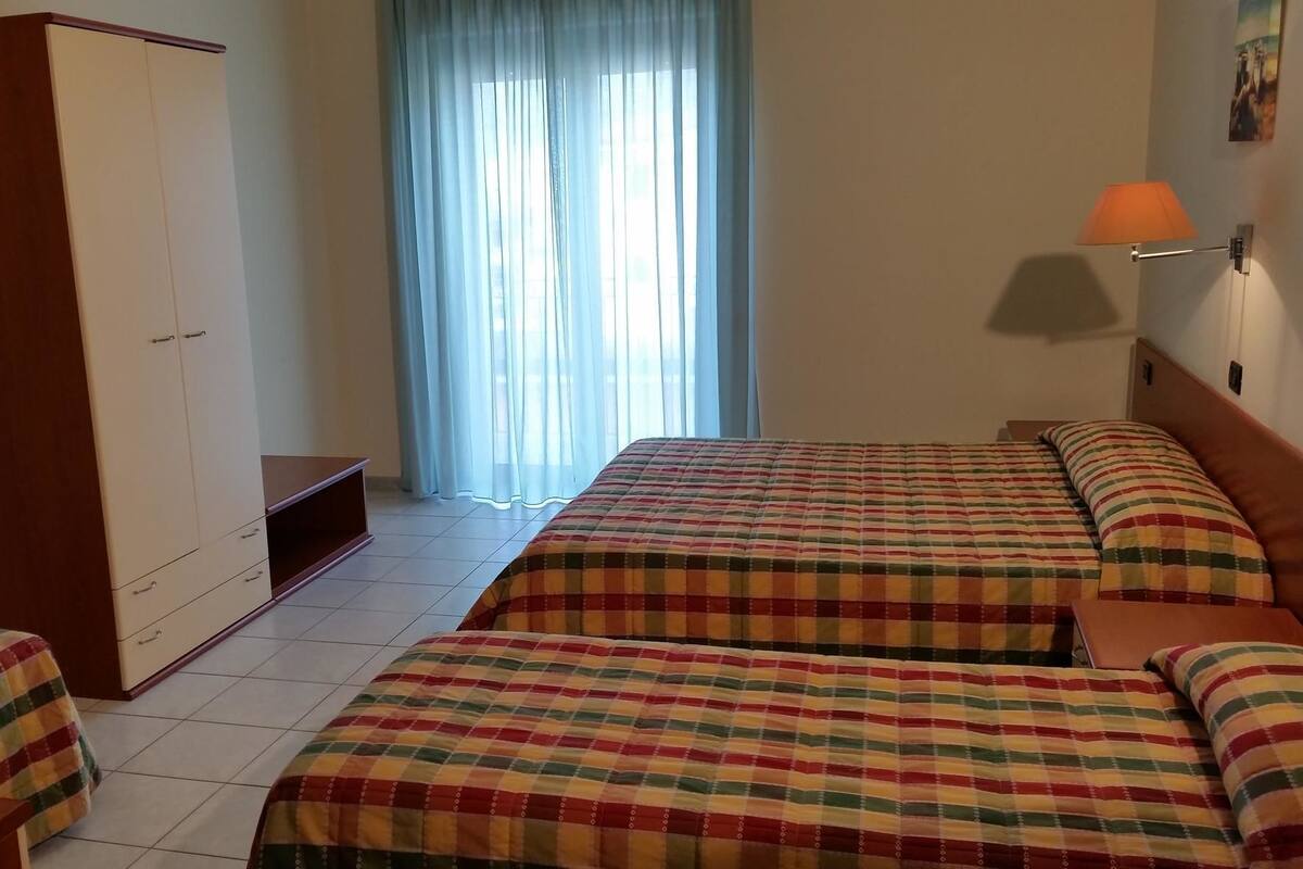 Une chambre avec deux lits, une armoire, un bureau et une lampe.