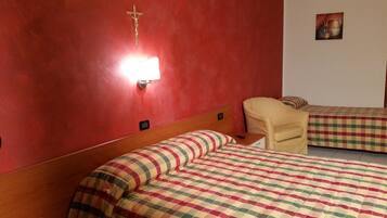 A hotel room with two beds, a nightstand, a chair, a wall-mounted light, and a painting.