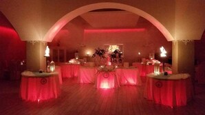 An indoor venue with a central stage, surrounded by tables with red lighting. - Hotel Leon (San Giovanni Rotondo)