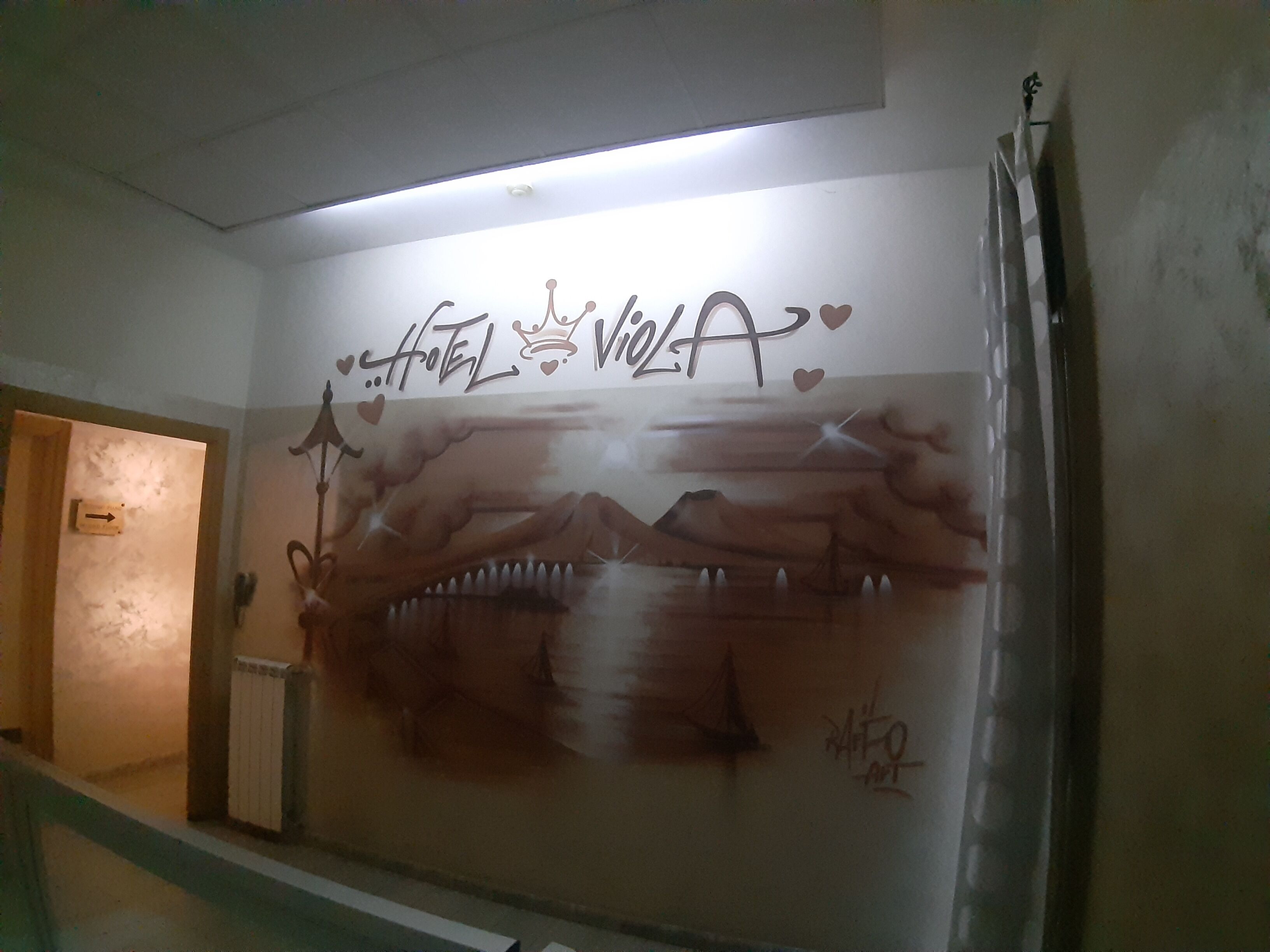 Paredes com grafite, incluindo as palavras "Hotel Vela" e uma paisagem de montanhas.