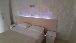 A neatly arranged bedroom with a bed, bedside tables, and a wall-mounted light fixture. - Hotel Viola (Naples)