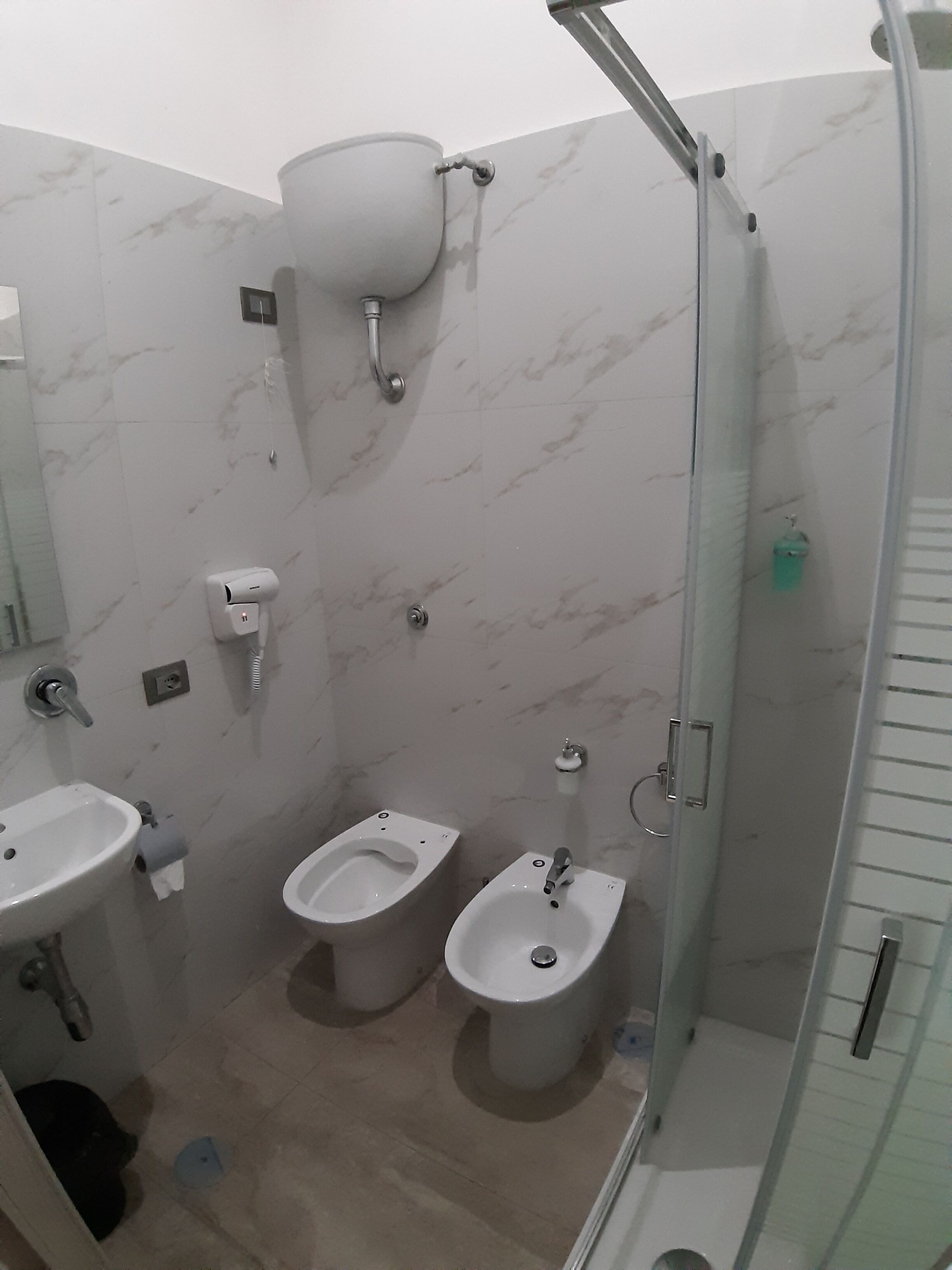 Et badeværelse med to håndvaske, toilet og bruser.