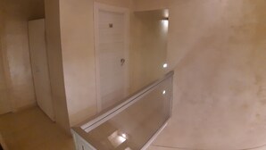 A room with a door, a mirror, and a light fixture on the wall. - Hotel Viola (Naples)