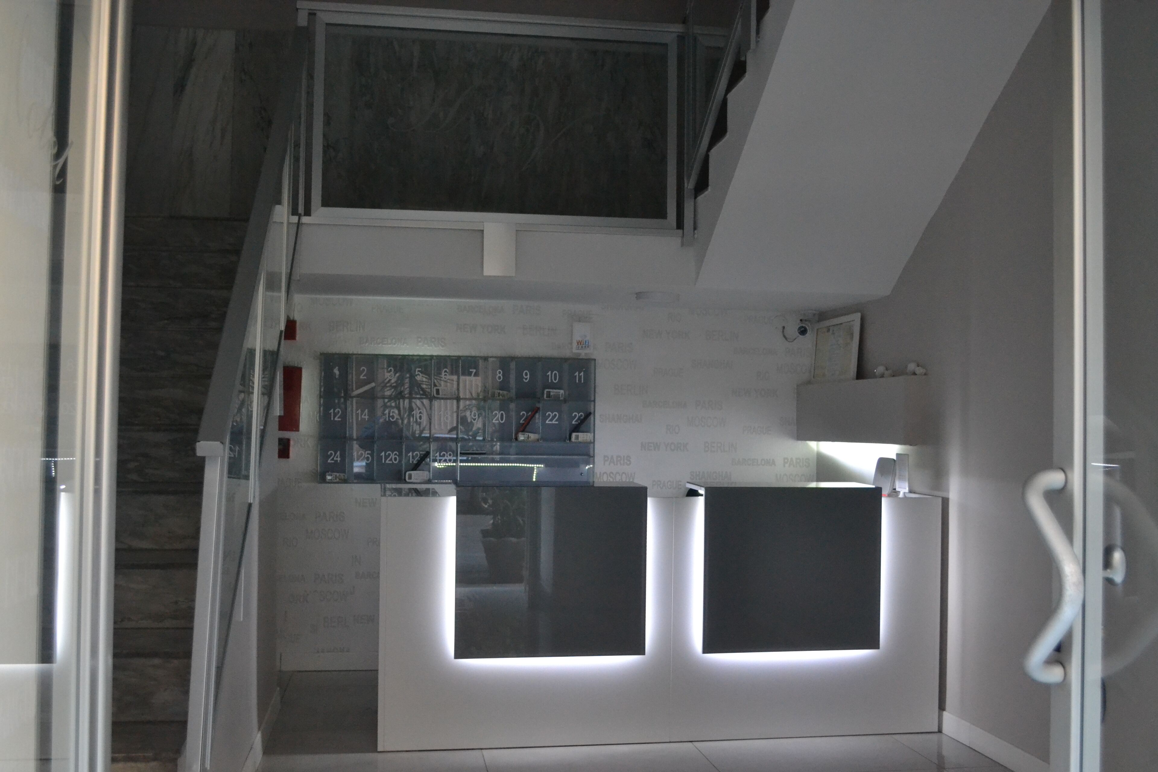 Ein modernes Interieur mit einer Treppe, die zu einer Zwischenebene führt. Eine Wand zeigt ein Bedienfeld mit beleuchteten Tasten.