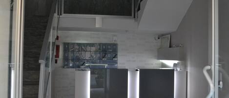 Ein modernes Interieur mit einer Treppe, die zu einer Zwischenebene führt. Eine Wand zeigt ein Bedienfeld mit beleuchteten Tasten.