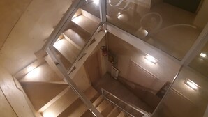 A multi-level interior with a staircase, glass railings, and a fire extinguisher on the wall. - Hotel Viola (Naples)
