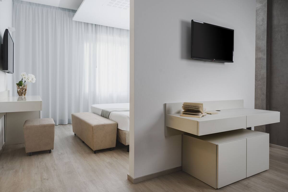 A modern bedroom with a bed, bedside table, and a mounted TV.