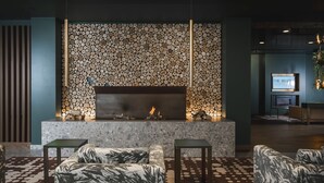 A modern lobby with a fireplace, seating area, and a wall decorated with logs. - The Regent Boutique Hotel & SPA  (Borgo Maggiore)