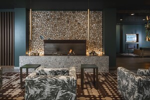 Um lobby moderno com lareira, área de estar e parede decorada com toras.