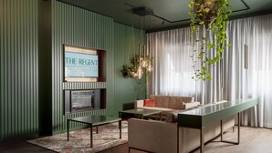 A modern living room with a sofa, a coffee table, and a TV mounted on the wall. - The Regent Boutique Hotel & SPA  (Borgo Maggiore)