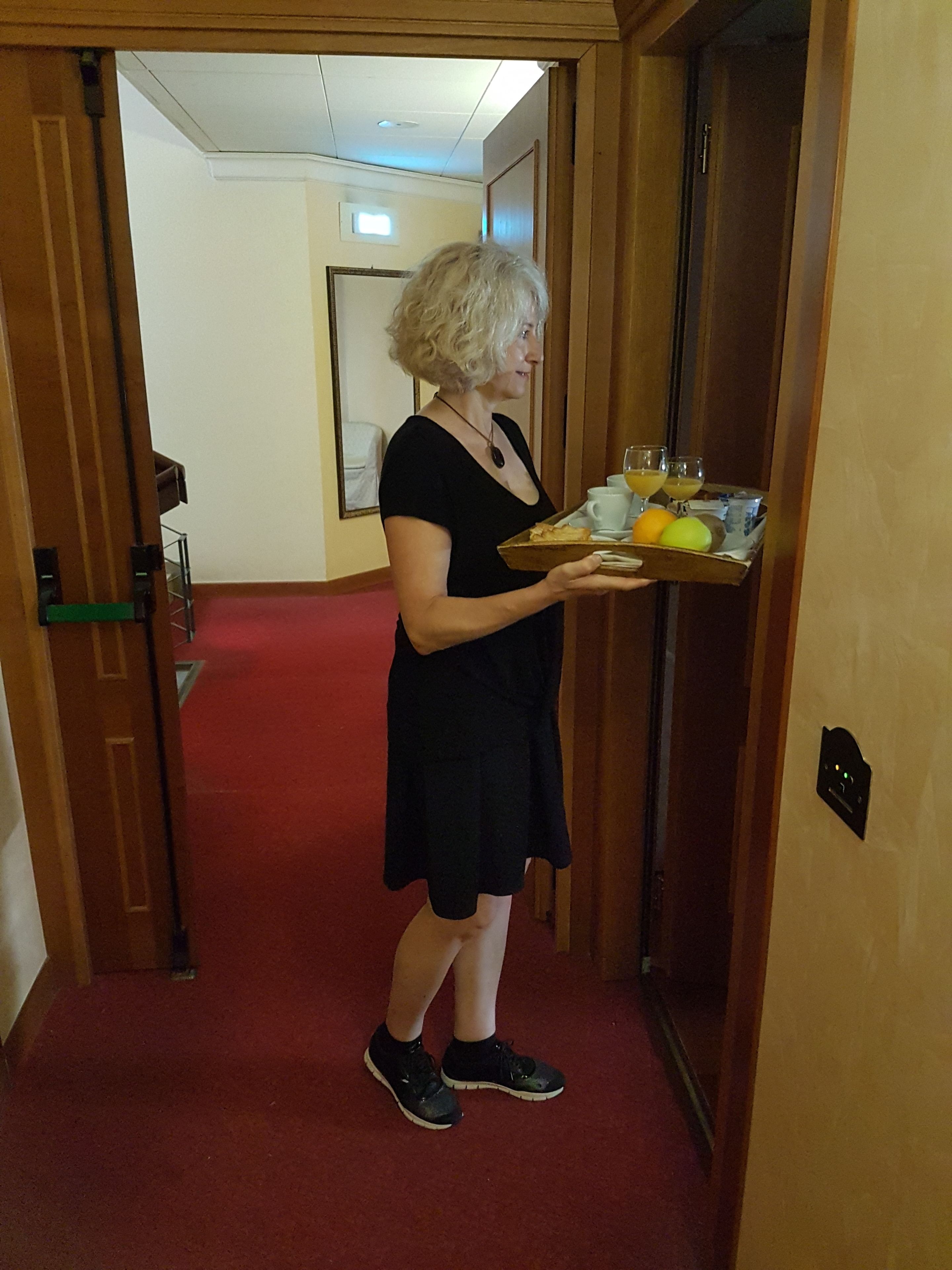 Una persona in un corridoio che tiene un vassoio con cibo e bevande.