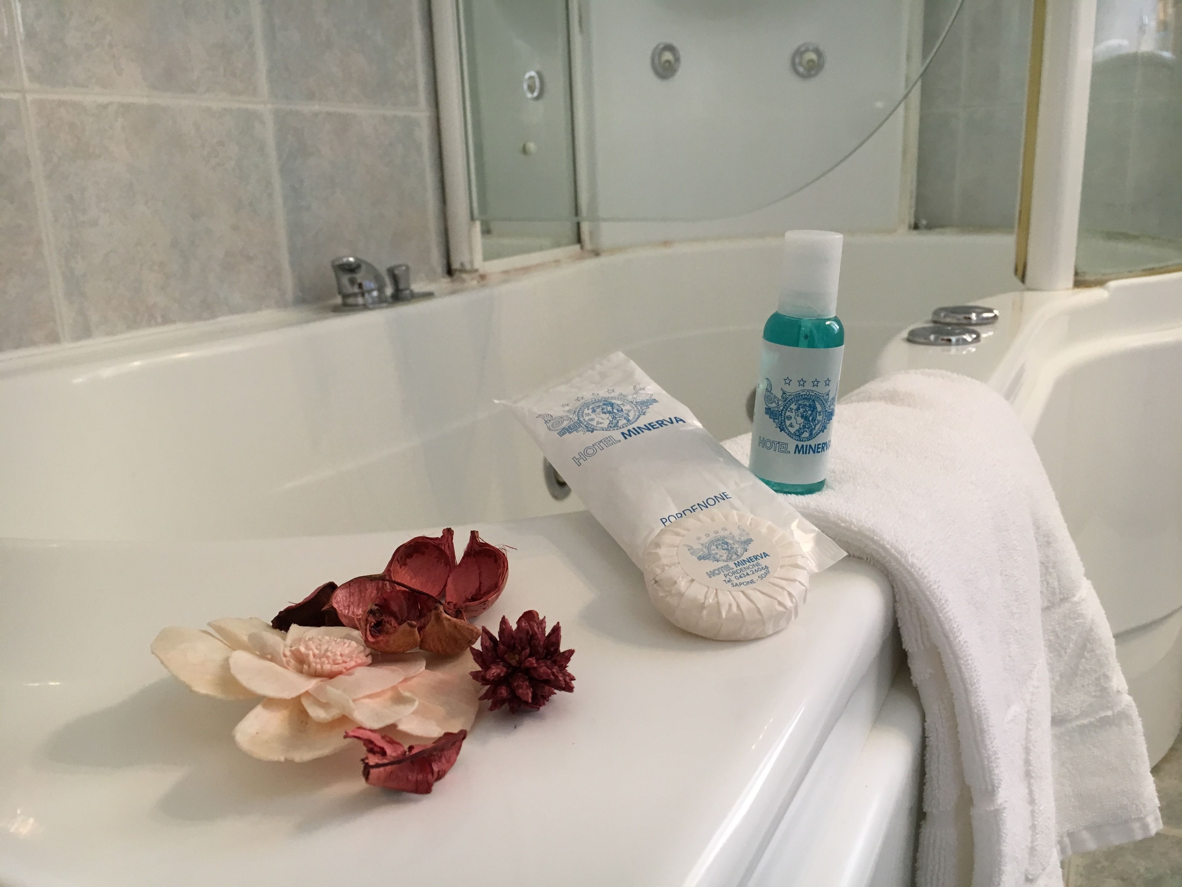 Un baño con una bañera, una toalla blanca, una botella de jabón y una presentación de jabón.