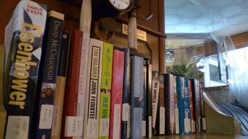 A bookshelf with various books, a clock, and a sign that reads "TATTOO MARE".
