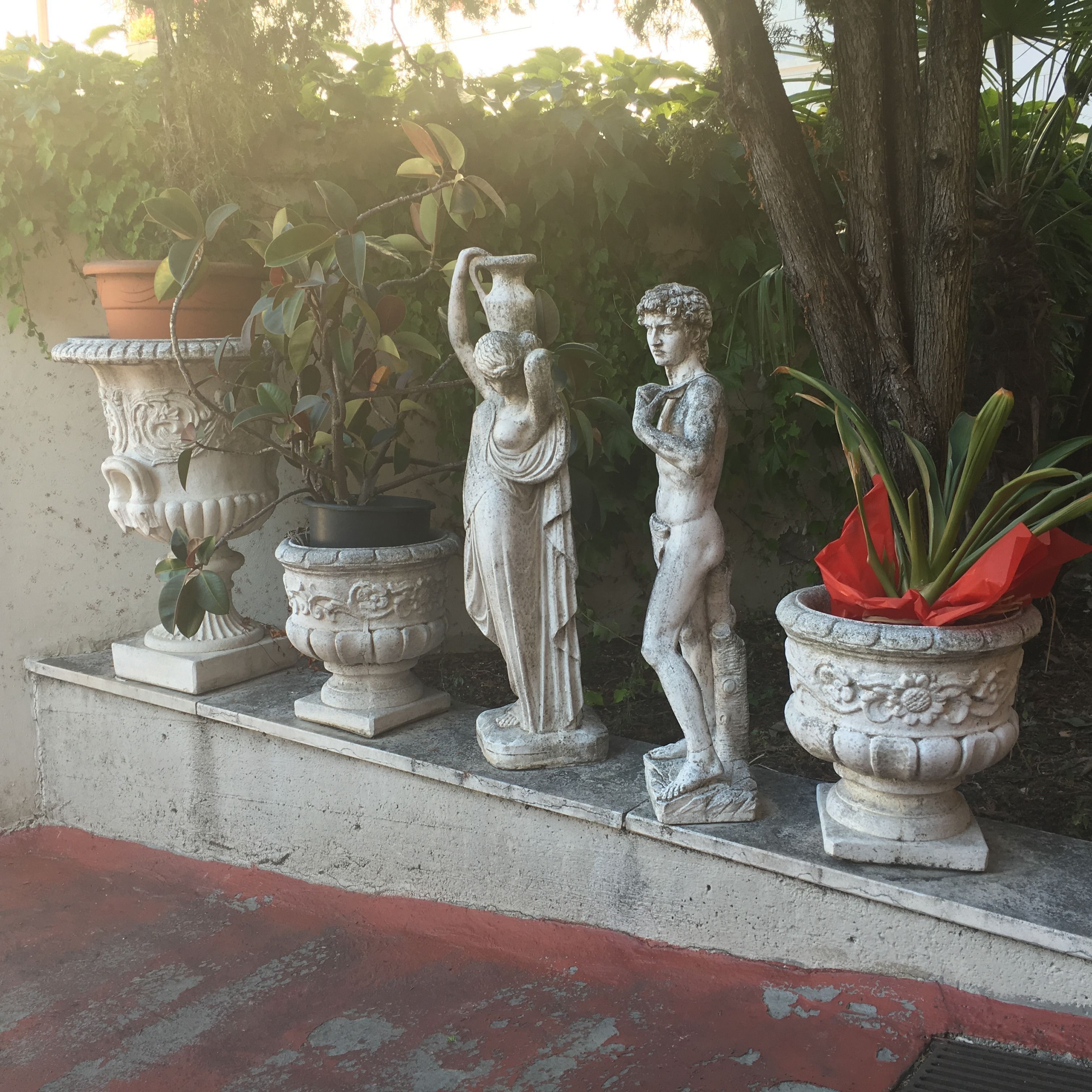 Un jardín con estatuas y plantas en macetas.