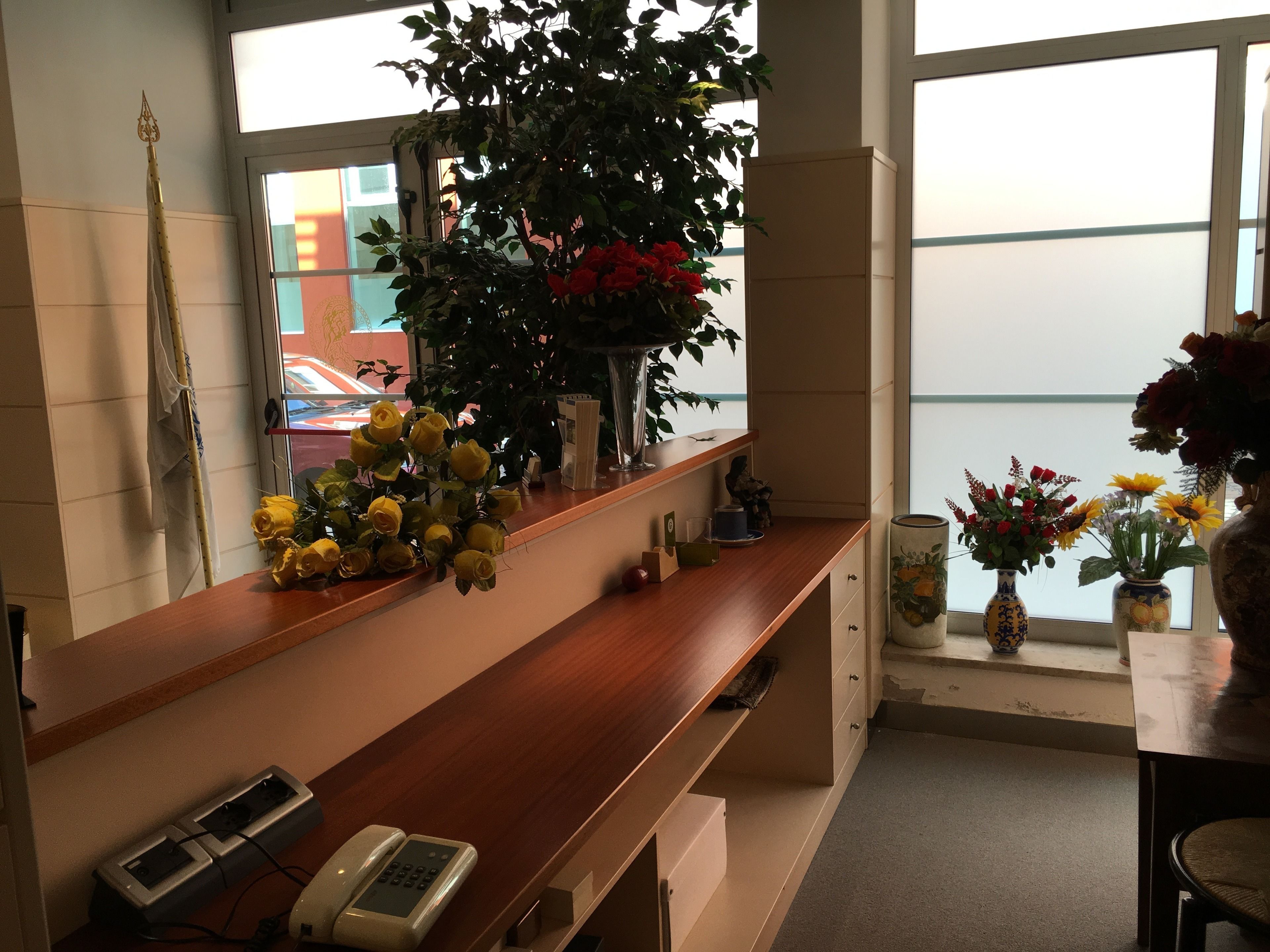 Un mostrador de recepción con un teléfono, una planta y varios objetos decorativos.
