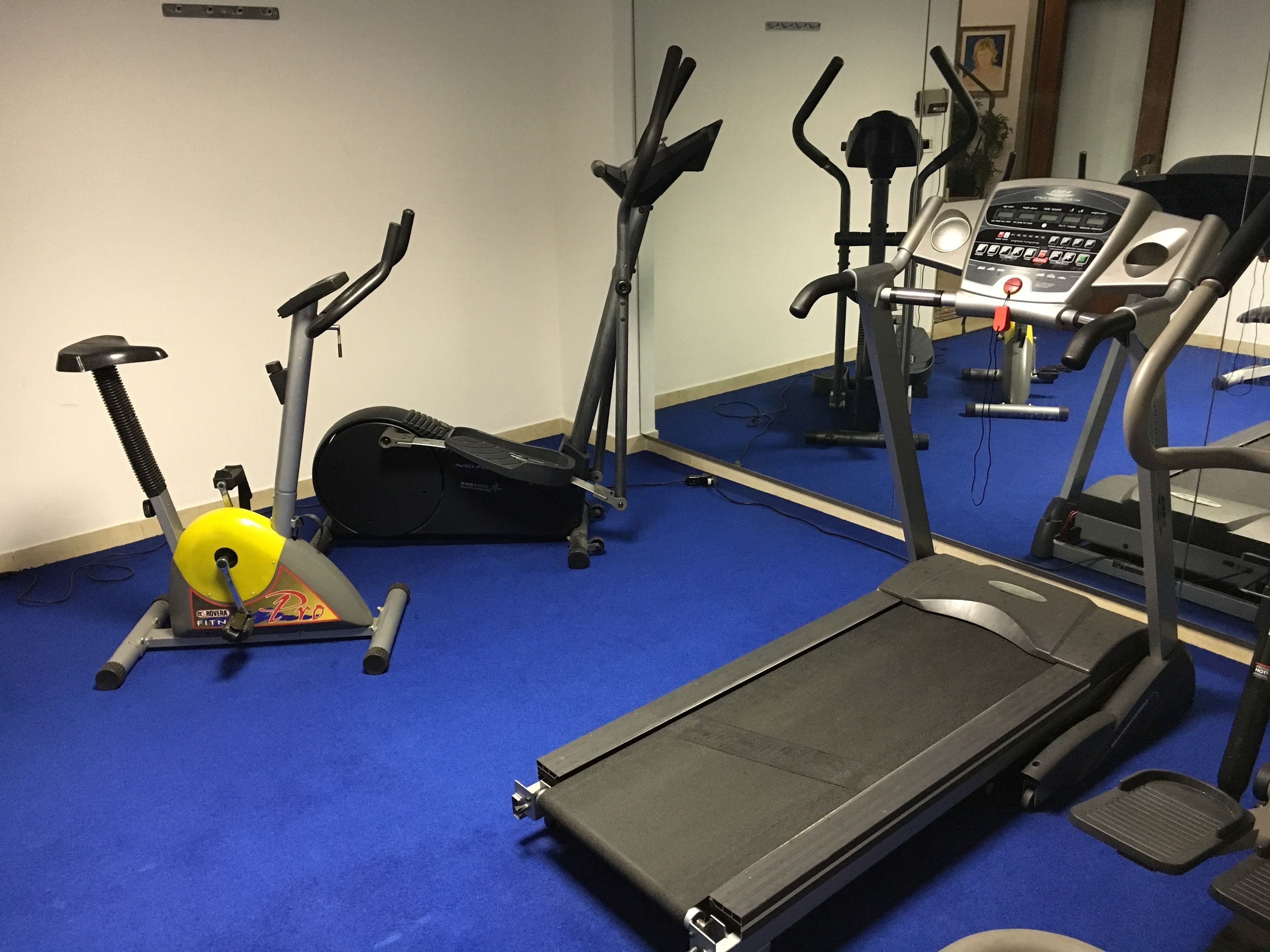 A gym with various exercise equipment including treadmills, stationary bikes, and elliptical machines.