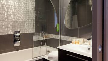A modern bathroom with a glass-enclosed shower, a white sink, and a dark tiled wall.
