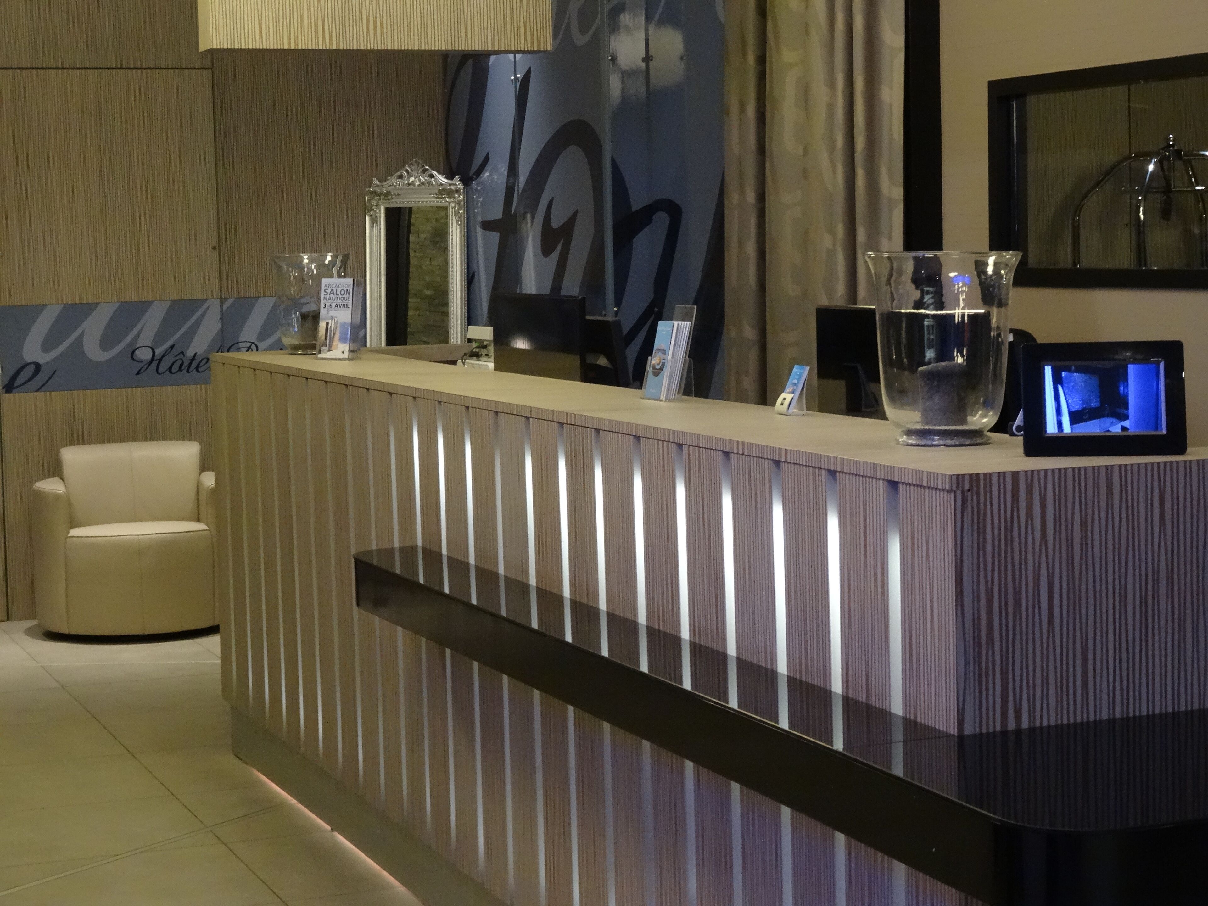 A reception desk with a modern design, a glass display case, and a digital screen.
