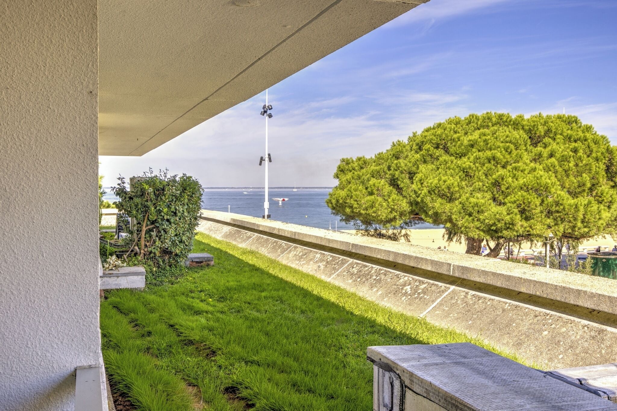 Un balcón con vistas al mar, un árbol y una farola.