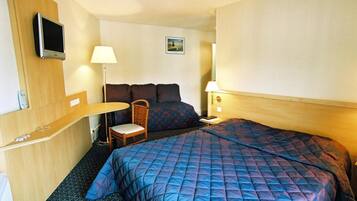 Une chambre d’hôtel avec un grand lit, une petite table, une chaise, un téléviseur et un tableau au mur.