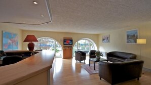 Vestíbulo de hotel con recepción, zona de estar y grandes ventanales.