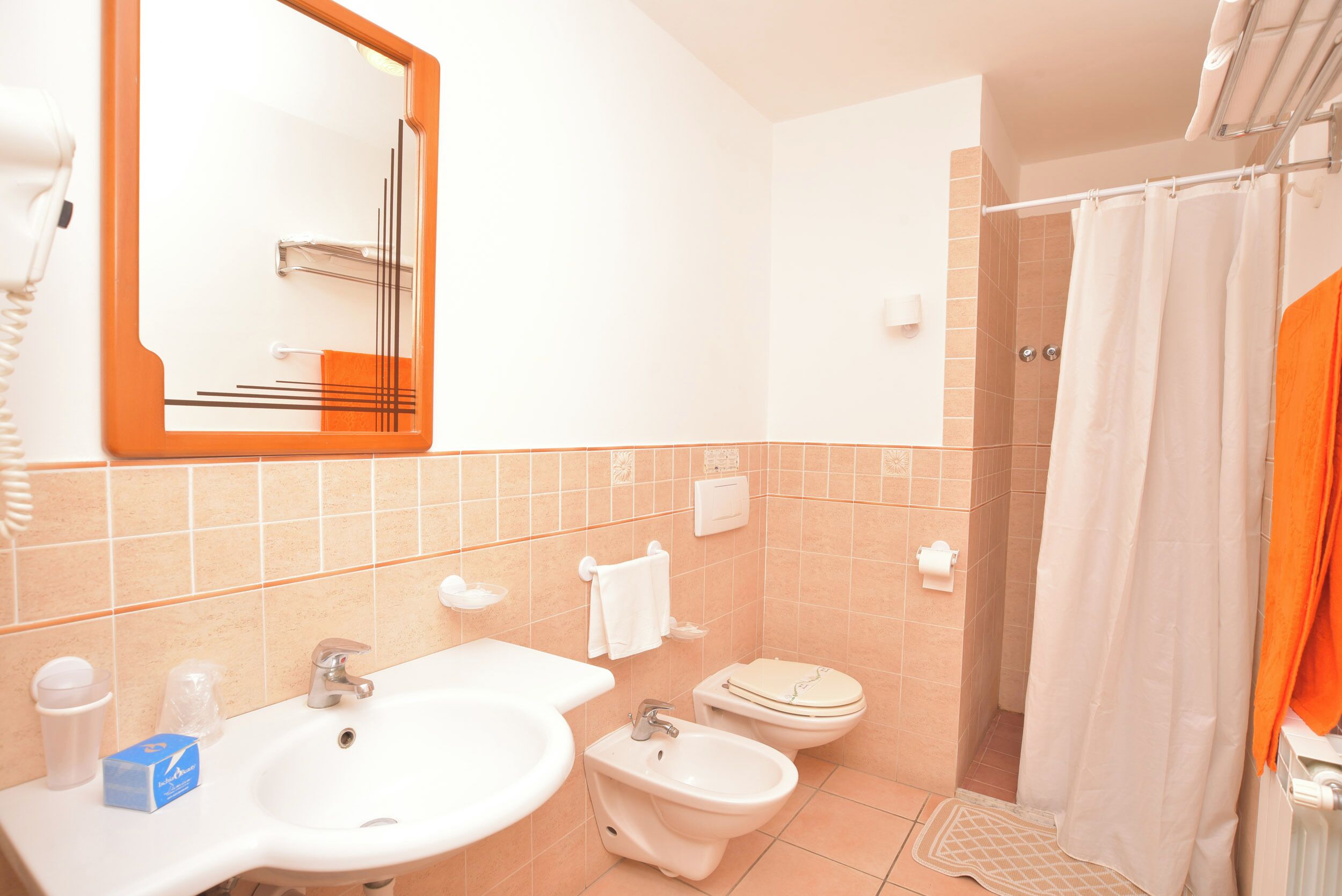 A bathroom with a sink, bidet, toilet, and shower curtain.