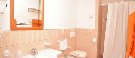 A bathroom with a sink, bidet, toilet, and shower curtain.