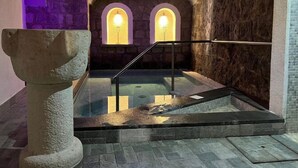 A stone-walled room with a central pool, stone benches, and arched windows. - Hotel Terme Zi' Carmela (Forio)