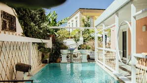 A swimming pool with a pergola, potted plants, and a view of a building in the background. - Hotel Terme Zi' Carmela (Forio)