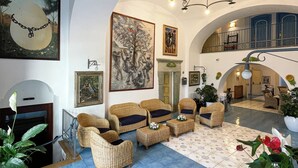 A spacious lobby with wicker furniture, a fireplace, and a large painting on the wall. - Hotel Terme Zi' Carmela (Forio)