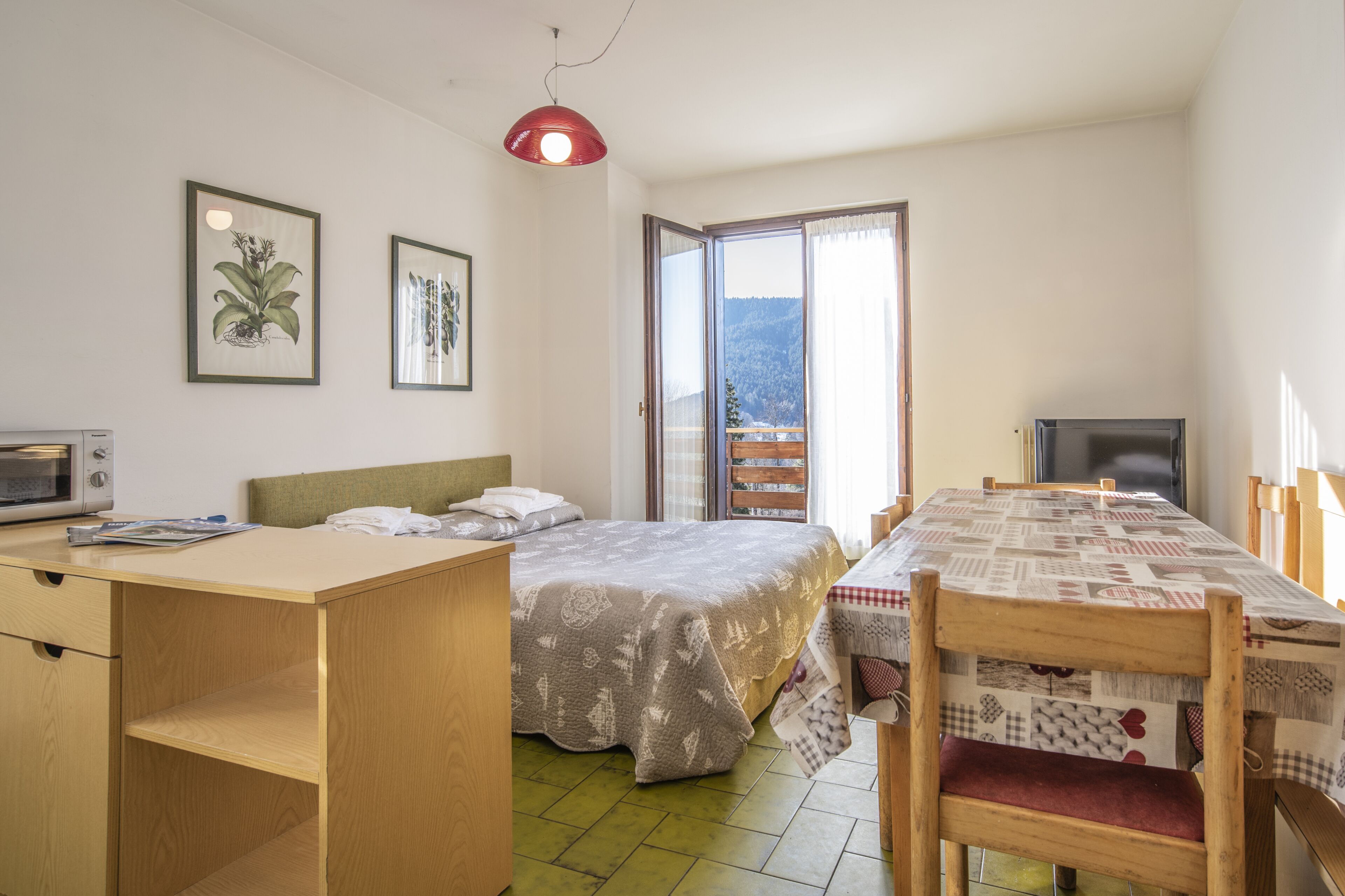Un dormitorio con cama, escritorio, mesa de comedor y televisor.