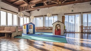 Amplio espacio interior para juegos con piso de madera, una casita de juegos y un banco.