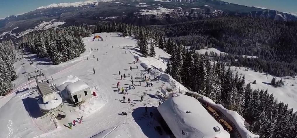 A ski resort with multiple buildings, ski lifts, and a snowy landscape.