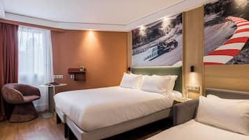 A hotel room with two beds, a small table with a plant, a chair, and a large wall mural.