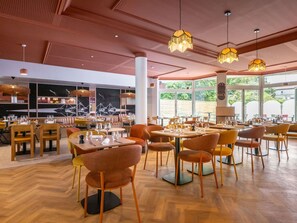 Interior de restaurante con suelo de madera, mesas, sillas y lámparas colgantes.