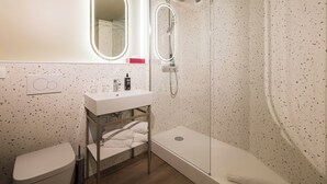 Un baño moderno con ducha independiente, tocador con espejo y retrete.