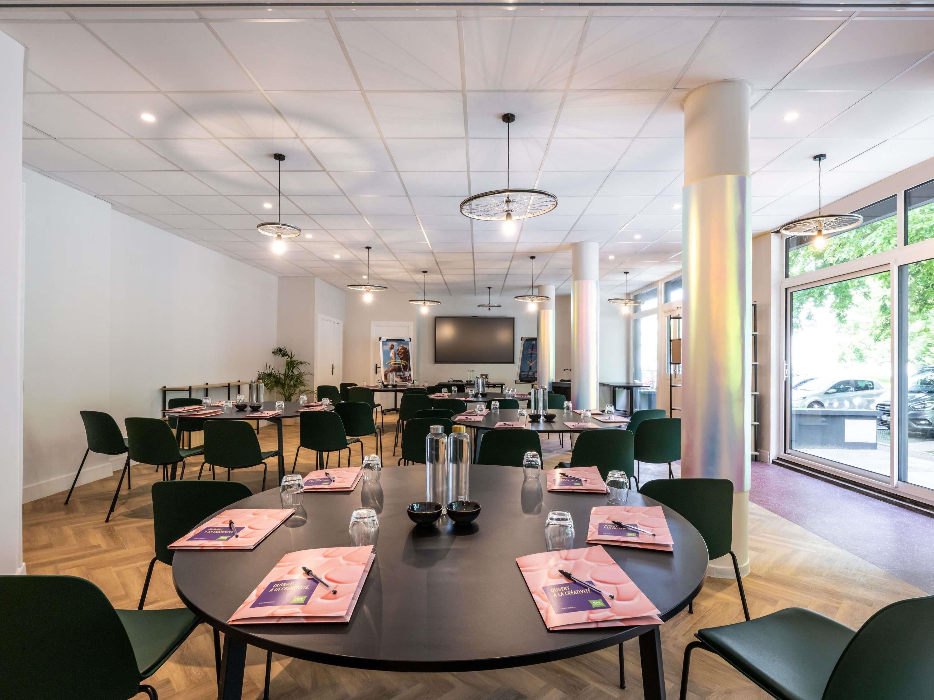 Un salón de conferencias con mesas redondas, sillas y una pantalla grande.