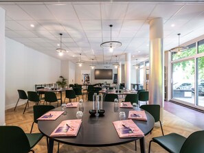 Un salón de conferencias con mesas redondas, sillas y una pantalla grande.