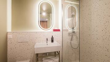 Un baño con un lavabo blanco, ducha con cerramiento de cristal y espejo con iluminación.