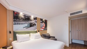 Una habitación de hotel con una cama grande, una mesita de noche, una silla y un armario.
