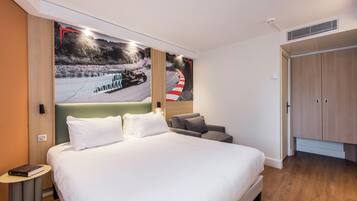 A hotel room with a large bed, a bedside table, a chair, and a wardrobe.