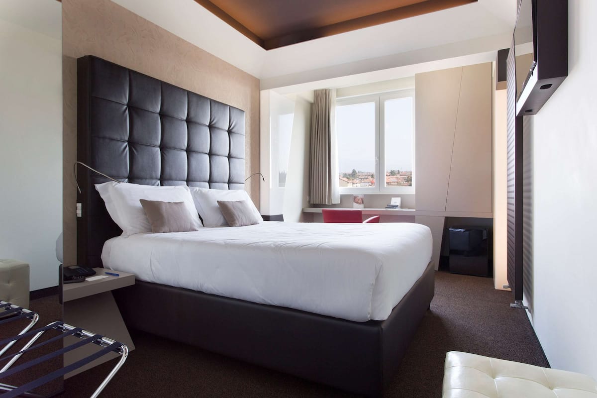 Una camera d'albergo moderna con un letto grande, una scrivania e vista sulla città.