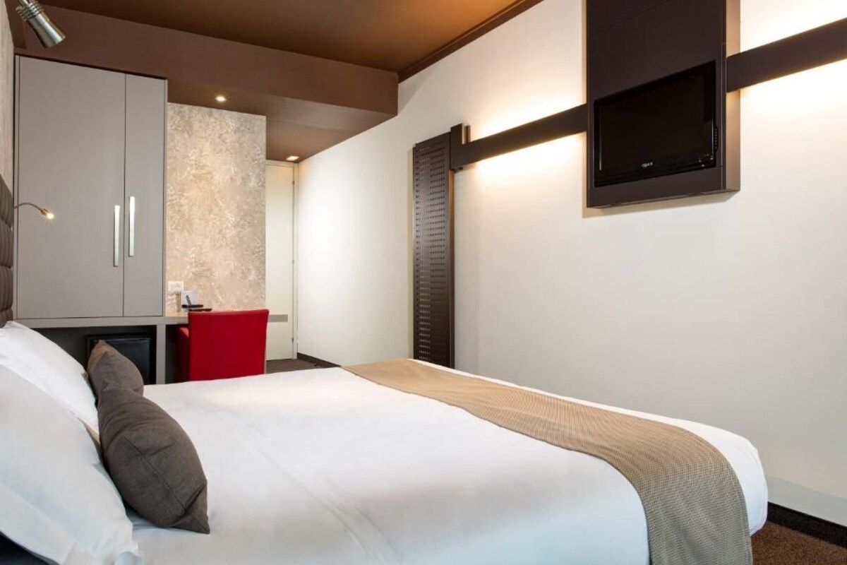 Una habitación de hotel con cama, escritorio y televisión.