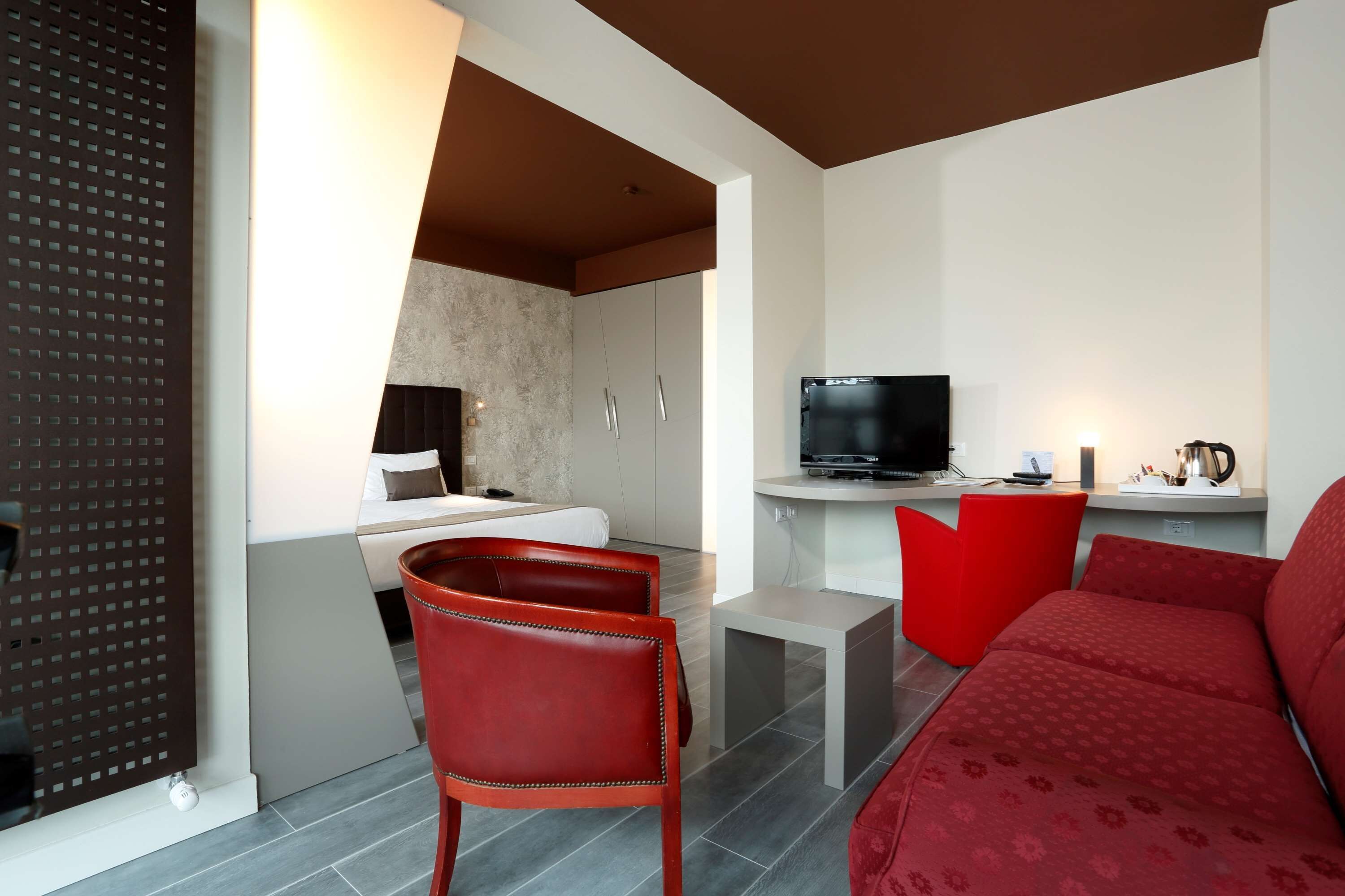 A modern living room with a red sofa, a red chair, a TV, and a small table.