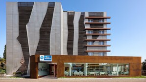 A modern hotel with a distinctive facade, a central entrance, and a visible outdoor seating area.