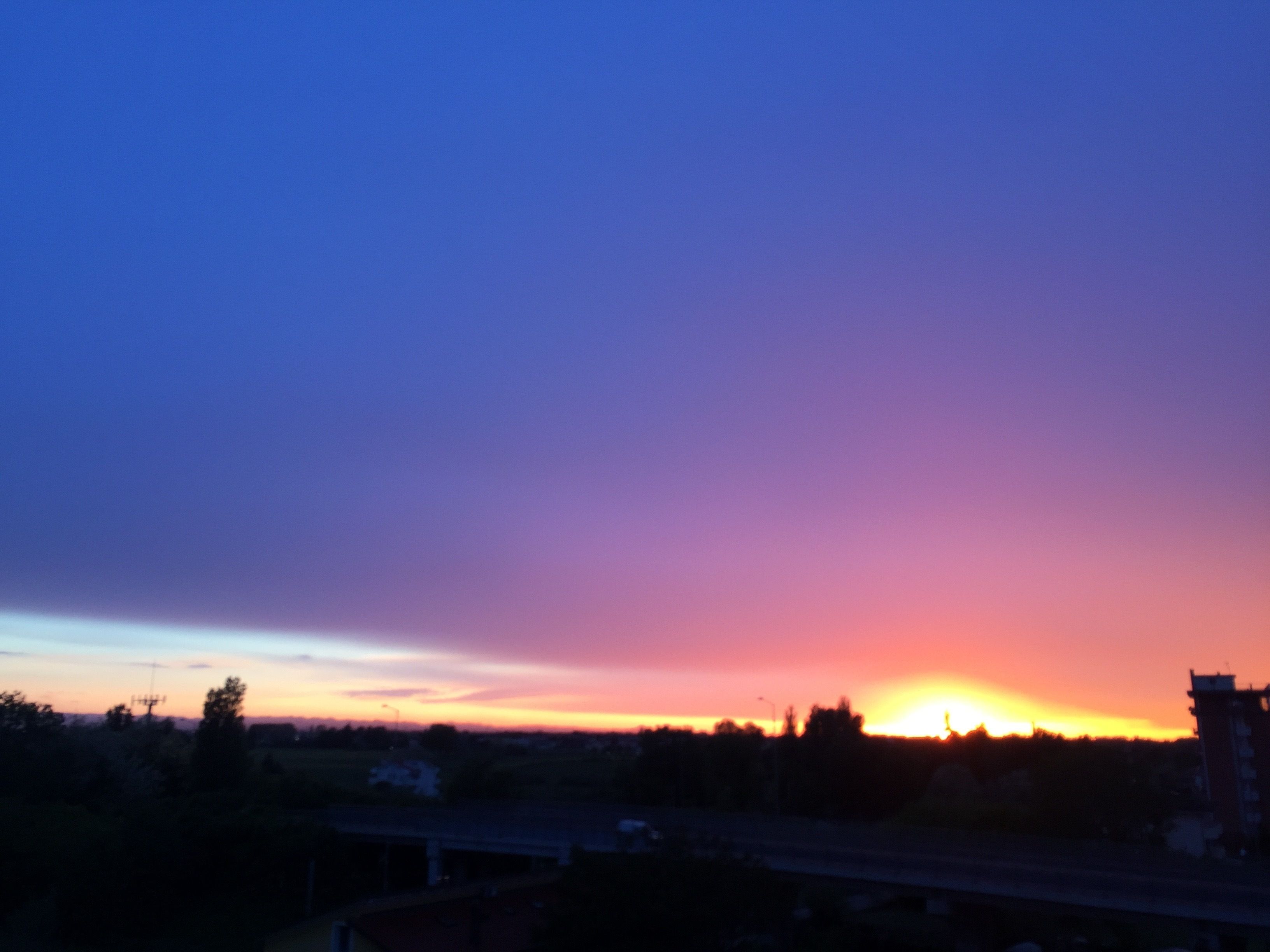 Un atardecer sobre un paisaje con una autopista y edificios al frente.