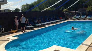 En swimmingpool med liggestole og et område med jacuzzi.