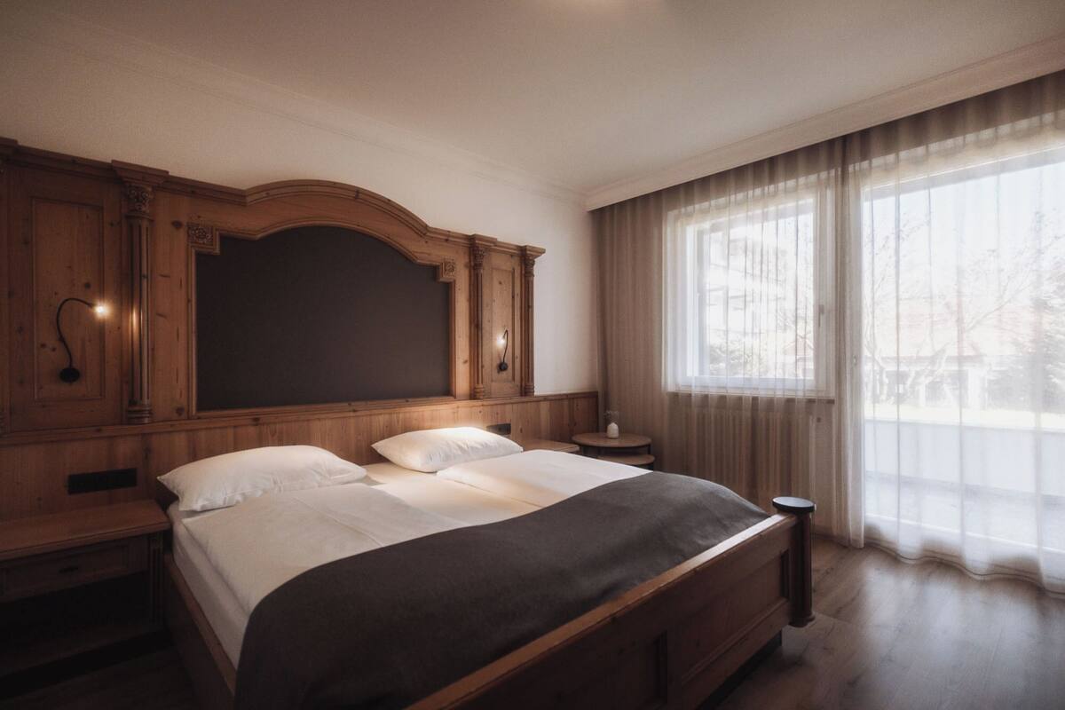 Une chambre à coucher avec un grand lit, une tête de lit en bois et une petite table de chevet.