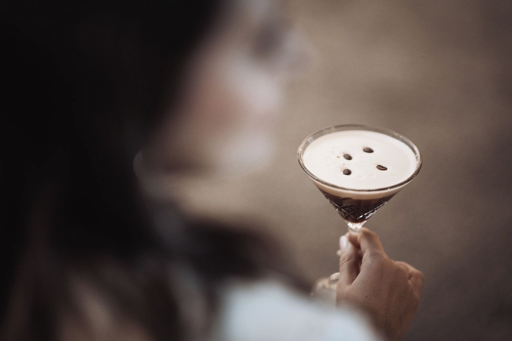 A person holding a martini glass with a frothy top.